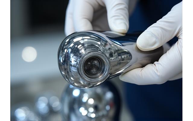 Technician inspecting a highly polished metal component reflecting light, demonstrating a perfect surface finish.